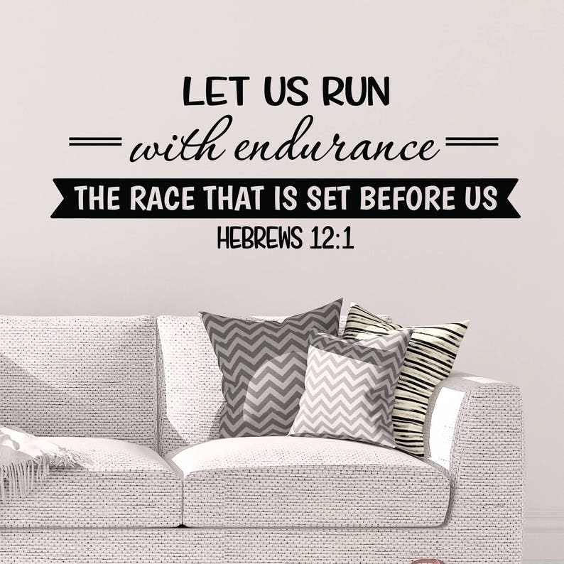 May include: Black and white wall decal with the quote "Let us run with endurance = The race that is set before us = Hebrews 12:1". The decal is displayed on a white wall above a white couch with gray and white patterned pillows.