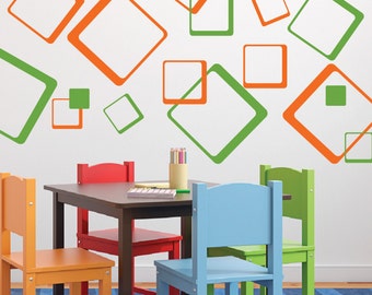 May include: A set of four colorful wooden chairs and a brown wooden table with a white wall decorated with orange and green geometric shapes.