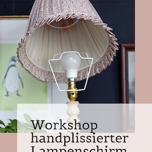 May include: A pleated lampshade with a small-scale floral pattern in shades of pink, blue, and white, featuring a ruffled edge and a white metal frame. The text Workshop handplissierter Lampenschirm 6.-7. September 2026 is visible.