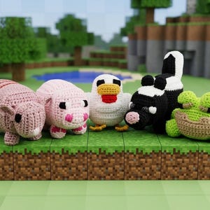 Puede incluir: Figuras de animales de ganchillo hechas a mano: un armadillo rosa, un cerdo rosa, una gallina blanca, una vaca negra y blanca y una rana verde. Se muestran sobre una plataforma de estilo bloque.