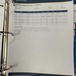 Peut inclure: Un exemple de journal d'inspection de porte coupe-feu sur papier blanc dans un classeur bleu à trois anneaux. Le document comprend un tableau avec des colonnes pour l'ID de porte, l'emplacement, le type, la classification et l'état, daté du 12/09/2026.