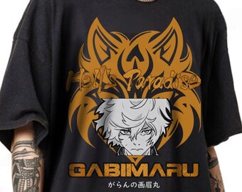 May include: A black short-sleeve t-shirt featuring a large orange graphic of a stylised wolf head behind a grayscale anime character portrait. The text reads Hell's Paradise, GABIMARU, and Japanese characters in a bold, blocky font style.