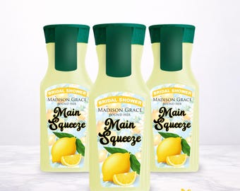 May include: Three identical plastic bottles with dark green caps and pale yellow liquid. The labels feature a lemon graphic, green leaves, and the text: Bridal Shower, Madison Grace Found Her, Main Squeeze, in black and white lettering.