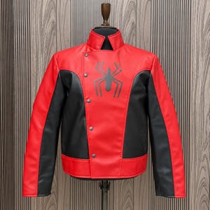 May include: A red and black faux leather jacket featuring a stand-up collar, a diagonal front closure with four silver-toned metal snap buttons, and a large black spider graphic printed on the upper right chest area.
