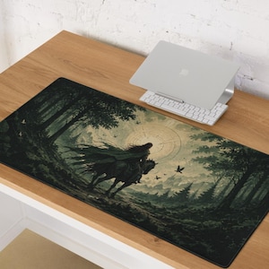 Op de afbeelding: Een rechthoekige bureaumat met een donkere, sfeervolle illustratie van een figuur in een mantel op een paard, rijdend door een dicht bos naar een gloeiende cirkelvormige zon. De scène bevat silhouetten van vogels in de lucht.