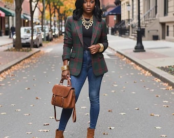 Puede incluir: Un blazer verde oscuro con patrón de cuadros rojos, una blusa negra, pantalones vaqueros azules y botines de ante marrón. El conjunto incluye un bolso de cuero marrón, un collar de cadena dorada y brazaletes dorados en ambas muñecas.