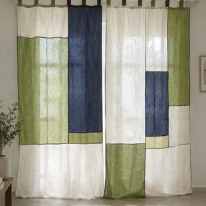 May include: A pair of floor-length curtains featuring a colour-blocked pattern of off-white, olive green, and navy blue rectangular panels. The curtains are suspended from a white rod using fabric tabs at the top, creating a structured, layered look.