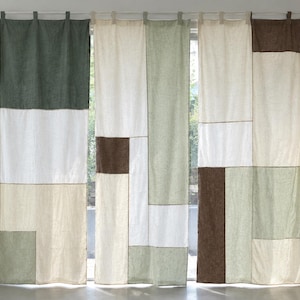 Op de afbeelding: Een set van drie kamerhoge gordijnen met een patchworkontwerp van rechthoekige stoffen panelen in de kleuren donkergroen, saliegroen, crème, wit en donkerbruin. De gordijnen zijn opgehangen aan een roede met behulp van stoffen lussen.