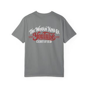 May include: A grey short-sleeved t-shirt featuring a graphic on the back. The text reads The Workin Kind Co. in white, YouTube in a stylised red script font, and CERTIFIED in white, all centred on the upper back of the garment.