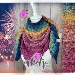 Op de afbeelding: Een driehoekige gehaakte sjaal met een kleurverloop van diepblauw naar goudgeel en magenta. De gestructureerde stof vertoont een geweven patroon en bevat een klein rechthoekig leren label aan de zijkant. De tekst "ophélja" is zichtbaar.