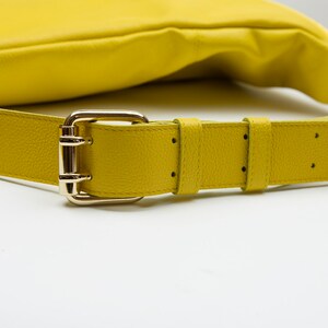 May include: A yellow leather shoulder bag with a gold buckle and strap.