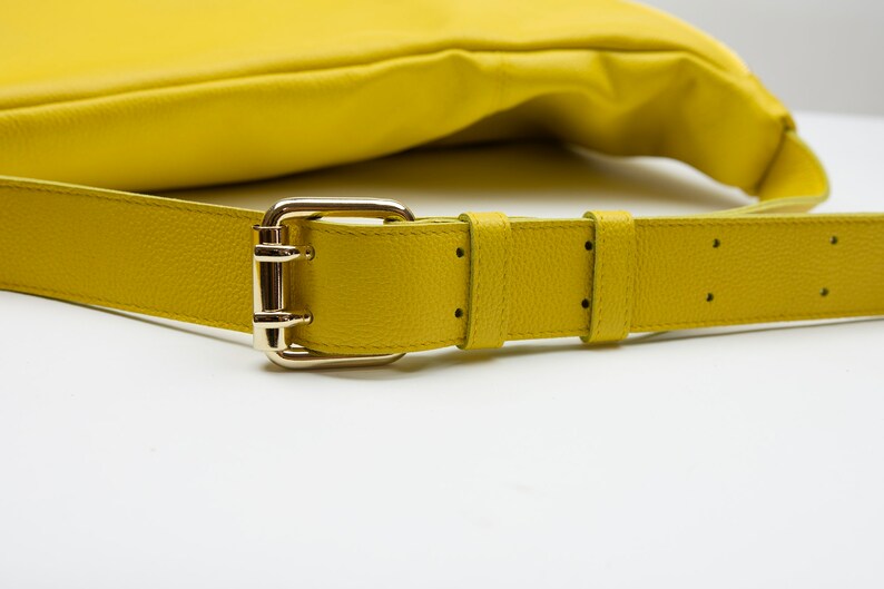 May include: A yellow leather shoulder bag with a gold buckle and strap.