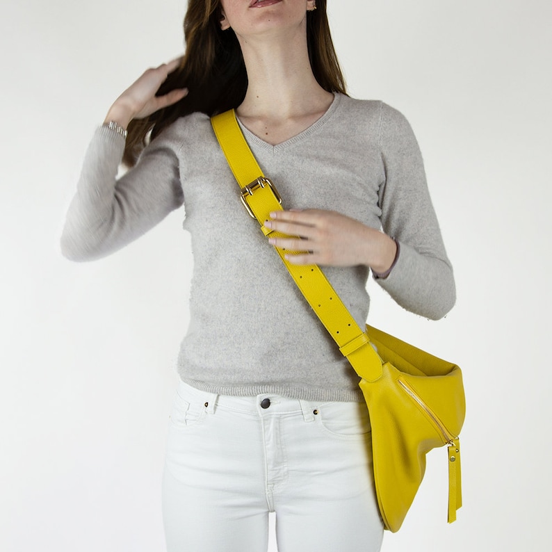 May include: A bright yellow leather crossbody bag with a long adjustable strap. The bag has a zipper closure and a small tassel.
