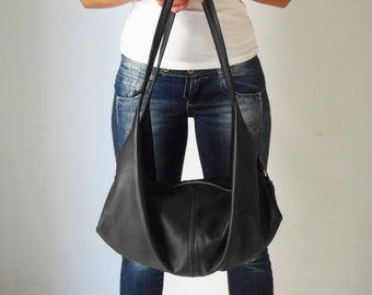 May include: A black leather tote bag with a slouchy design. The bag has two straps and a zipper closure.