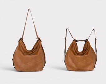Może przedstawiać: Jasnobrązowa torba typu hobo o miękkim kroju z regulowanymi paskami. Torba jest pokazana w dwóch konfiguracjach: jedna z pojedynczym długim paskiem na ramię, a druga z dwoma paskami w formie plecaka, obie z metalowymi elementami wykończeniowymi.