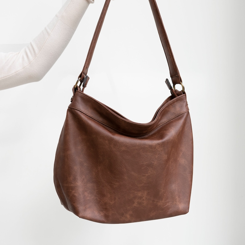 May include: A brown leather shoulder bag with a single strap. The bag has a slouchy, casual look.