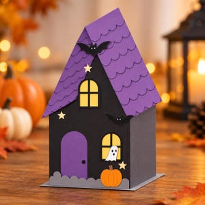 May include: A paper craft house featuring a black facade with a purple arched door, a purple scalloped roof, and yellow windows. The structure is decorated with black paper bats, small yellow stars, a white ghost figure, and an orange pumpkin.