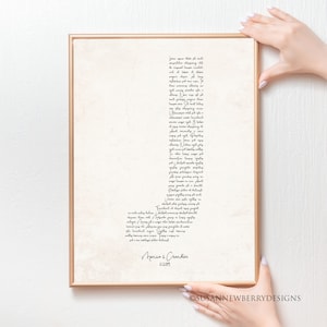 May include: A framed print with a beige background and a gold-colored frame. The print features a large letter "J" composed of handwritten text. The names "Monica & Chandler" and the date "11.2.09" are at the bottom.
