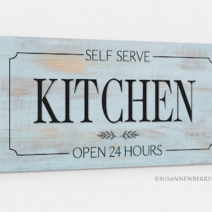 May include: A blue and white wooden sign with the text "Self Serve Kitchen Open 24 Hours" in black lettering. The sign has a distressed look and a decorative border.
