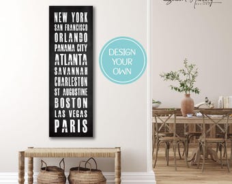 Può includere: Opera d'arte murale rettangolare nera con un elenco di città in testo bianco: New York, San Francisco, Orlando, Panama City, Atlanta, Savannah, Charleston, St. Augustine, Boston, Las Vegas e Parigi. Un cerchio azzurro con "DESIGN YOUR OWN".