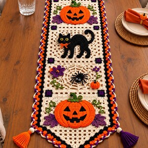 Peut inclure: Un chemin de table en crochet rectangulaire avec une base en grille crème et des bordures orange, noires et violettes. Il est orné d'appliques de deux citrouilles d'Halloween, d'un chat noir, de deux araignées sur toiles, de fleurs violettes et de pompons orange.