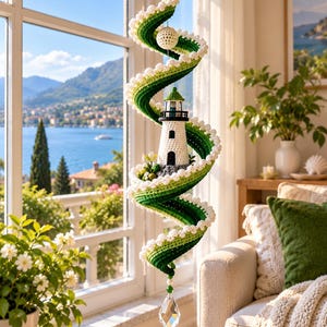 May include: A hanging spiral decoration featuring a crocheted lighthouse in white and black, surrounded by a green and white crocheted ribbon structure. The piece is accented with white beads and a clear, faceted crystal drop at the bottom.