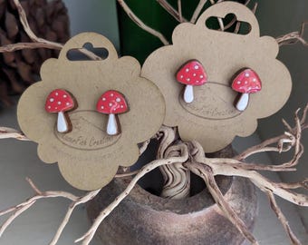 May include: A pair of red and white mushroom stud earrings on a brown card with the text "Leaf Fish Creations".