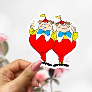 May include: Two cartoon characters with red and yellow outfits, blue bow ties, and pointed hats. They are both smiling and have their arms raised in the air.