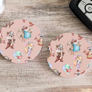 May include: Two round pink coasters with a repeating pattern of cartoon chipmunks and squirrels. The chipmunks and squirrels are wearing different outfits and hats.