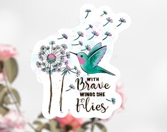 May include: A teal blue hummingbird with pink accents flies towards a dandelion with white seeds blowing in the wind. The text "With Brave Wings She Flies" is written in black cursive lettering.