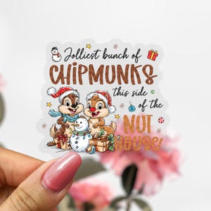May include: A sticker featuring two cartoon chipmunks wearing Santa hats and scarves, with a snowman and gifts. The text reads "Jolliest bunch of Chipmunks this side of the Nut House."
