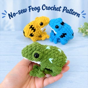 Puede incluir: Tres ranas de ganchillo en amarillo, azul y verde con ojos de plástico negro y cuerpos de hilo texturizado. El texto No-sew Frog Crochet Pattern aparece en la parte superior. La rana verde tiene detalles en verde claro en el lomo.