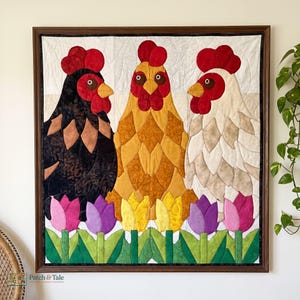 Könnte beinhalten: Ein gerahmter Wandbehang aus Stoff mit drei Hühnern in Schwarz, Gold und Weiß, jeweils mit rotem Kamm und gelbem Schnabel. Die Hühner stehen hinter einer Reihe bunter Stofftulpen in Rosa, Violett und Gelb mit grünen Stielen und Blättern.