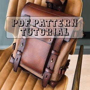 Pode incluir: Uma mochila de couro castanho com uma aba estruturada, alças verticais com tachas metálicas e uma pega superior. O texto PDF PATTERN TUTORIAL está sobreposto no centro da mala. O design inclui um compartimento principal e fivelas.