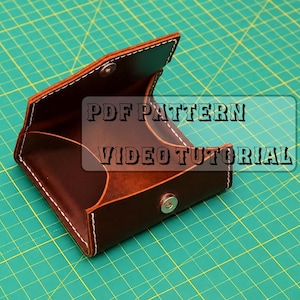 May include: A brown leather coin pouch with white stitching and a silver metal snap closure. The open pouch features a structured design with visible interior compartments. Text on the image reads PDF PATTERN VIDEO TUTORIAL.