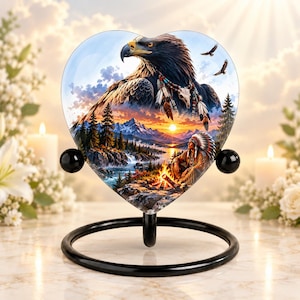 May include: A heart-shaped glass plaque featuring a detailed illustration of a bald eagle, a person in traditional headdress sitting by a campfire, and a mountain landscape. The plaque is supported by a black metal circular stand.