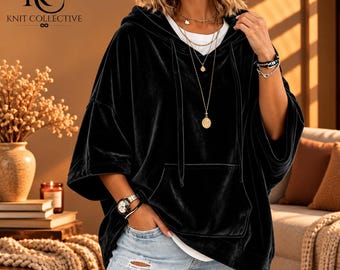 May include: A black velvet hooded pullover with short, wide sleeves and a front kangaroo pocket. The garment features a drawstring hood and is worn over a white base layer, paired with light blue distressed denim jeans with visible knee rips.