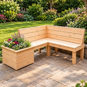 Puede incluir: Un banco de madera en forma de L con listones horizontales y una jardinera cuadrada integrada en un extremo. La estructura de madera clara incluye un respaldo y patas robustas, con la jardinera llena de flores de diversos colores.