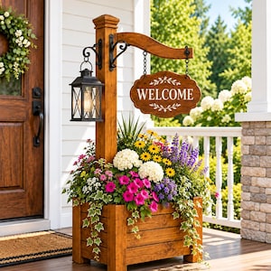 Op de afbeelding: Een houten plantenbak met een verticale paal, een zwarte metalen lantaarn en een hangend bord met de tekst WELCOME. De plantenbak is gevuld met een verscheidenheid aan kleurrijke bloemen, waaronder witte hortensia's, roze petunia's en gele margrieten.