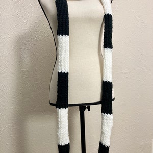 May include: A long black and white striped knitted scarf. The scarf is displayed on a white mannequin.