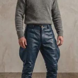 May include: A grey long-sleeved crew neck jumper paired with dark blue leather jodhpurs featuring flared thighs and fitted lower legs, worn with brown leather lace-up boots. The outfit combines a textured knit top with smooth leather trousers.