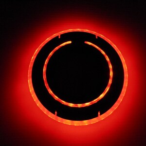 May include: A red glowing ring with a black center. The ring is made of a clear material and has a smooth surface.
