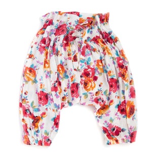 May include: White floral print pants with a gathered elastic waistband. The pants have a loose, flowing fit and are made of a lightweight fabric.