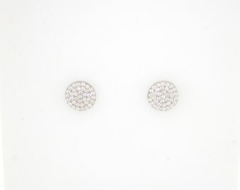 May include: Two round, silver-toned stud earrings. Each earring is covered with small, clear, sparkling stones. The earrings are set against a white background.