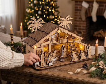 May include: A wooden nativity scene set featuring a stable structure with two palm tree cutouts on the roof, illuminated by internal string lights. The set includes various carved figures representing the holy family, animals, and wise men.