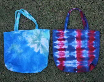 May include: Two tie-dye tote bags, one blue and green, the other red, white and blue.