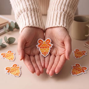 Stryk-på broderad lapp med rosett och tallkottemotiv (7,2 × 6,2 cm)