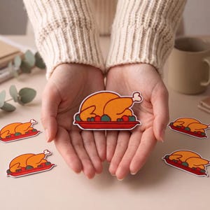 May include: An embroidered patch featuring a golden-brown roasted turkey served on a red platter with green and red side garnishes. The patch has a white border and is shaped like the turkey on the platter, showcasing detailed stitching throughout.