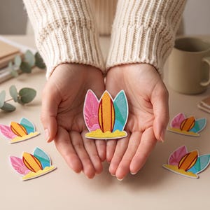 Op de afbeelding: Een geborduurde patch met een centraal oranje surfboard op geel zand, geflankeerd door een roze zonnestraalpatroon aan de linkerkant en een blauw golfpatroon aan de rechterkant, met een witte rand rondom het gehele grafische ontwerp.