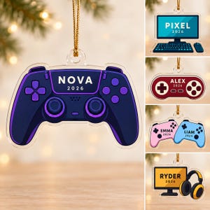 May include: A clear acrylic hanging ornament shaped like a video game controller in dark purple with light purple accents, featuring the text NOVA and 2026. Other variations include a computer, a red controller, two small controllers, and a monitor.